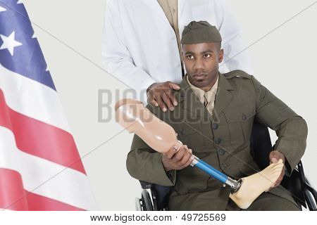Doctor with disabled military officer holding artificial limb as he looks at American flag