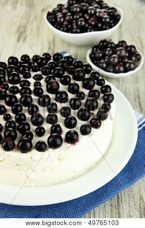 Cheesecake with fresh berries on white plate on wooden table closeup