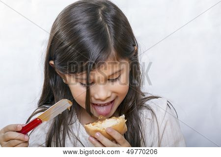 Long haired girl tries to prove bread slathered with sweet jelly