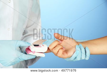Doctor measuring pulse rate and oxygen levels, on color background