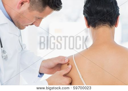 Male doctor examining melanoma on woman in clinic