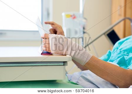 Midsection of male patient using tablet computer while relaxing in hospital room