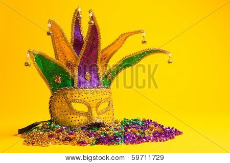 A festive, colorful group of mardi gras or carnivale mask on a yellow background.  Venetian masks.