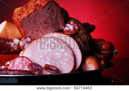 Lot of different sausages on salver on dark colorful background