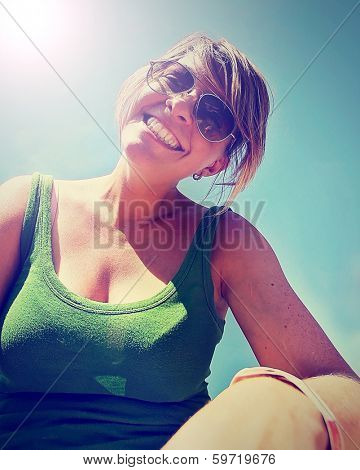 a cute girl smiling at the camera on a bright sunny day done with a retro vintage instagram filter