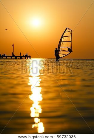 Silhouette of surfer at sunset passing by