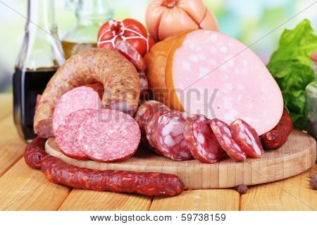 Different sausages on wooden table on natural background
