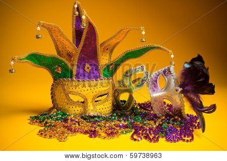 A festive, colorful group of mardi gras or carnivale mask on a yellow background.  Venetian masks.