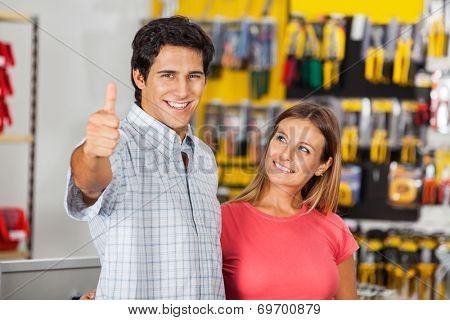 Portrait of successful man gesturing thumbsup with woman in hardware store