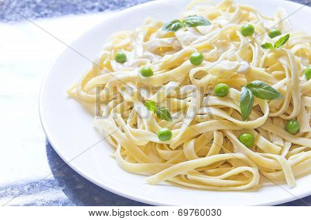 Fettuccini Alfredo primavera with peas and fresh basil leaves