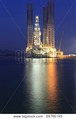 Jack Up Oil Drilling Rig In The Shipyard For Maintenance At Sunset Time