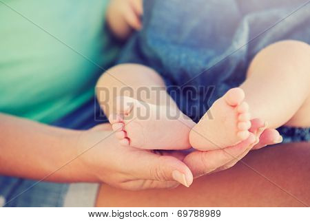 Mother holding adorable newborn baby feet