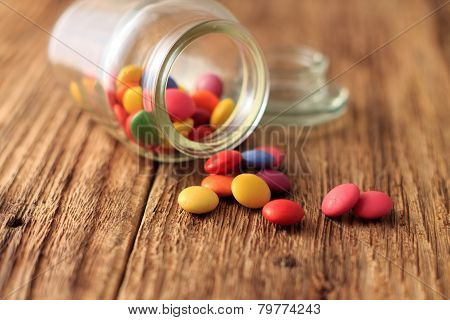Color Smarties Around Glass Dose On Wooden Board