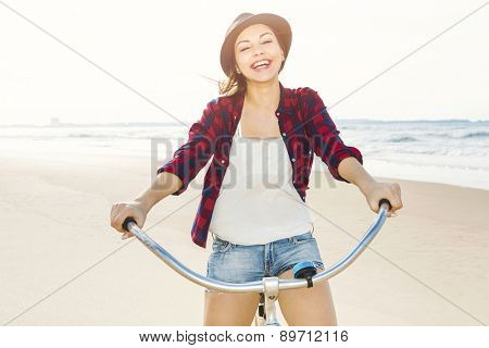 An attractive young woman riding her bicycle on the beach