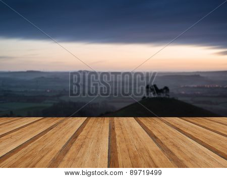 Beautiful Sunrise Dawn Landscape Of Hills Overlooking Brightly Lit Town In Valley Below With Wooden