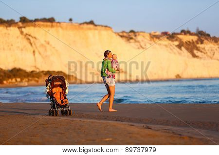 Affectionate Mother Holding And Kissing Her Baby On Beach