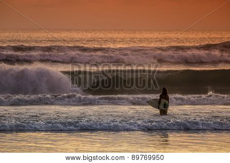 Surfer On The Beach At Sunset Tme