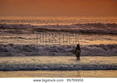 Surfer On The Beach At Sunset Tme