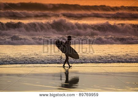 Surfer On The Beach At Sunset Tme