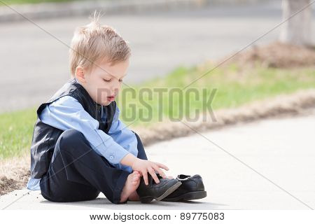 adorable toddler boy trying to put his shoes on