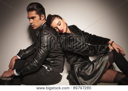Sexy young fashion woman leaning her head on her lovers shoulder while he is sitting with his legs cossed.