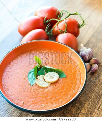 A bowl of tomato soup gaspacho with basil and crackers