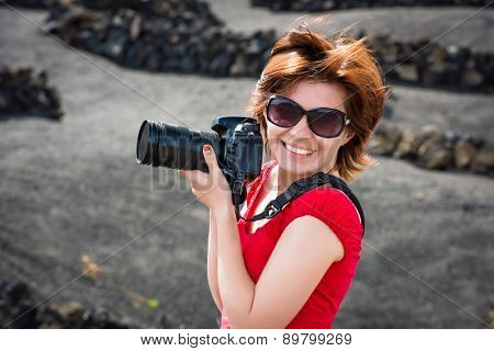 beautiful young woman in evening red dress and sunglasses with pfoto camera outdoors