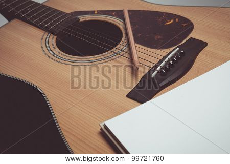 Pencil and paper on guitar in vintage style