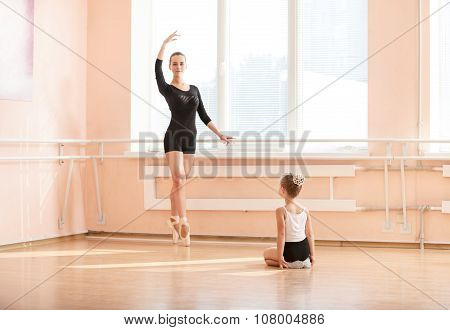 Girl beginner watching classmate standing en pointe.