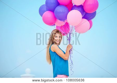 Beautiful young woman with a bunch of balloons