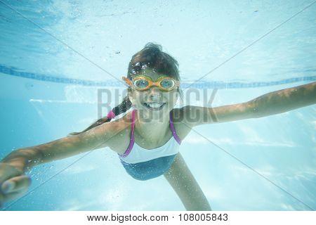 Joyful girl swimming underwater in pool.