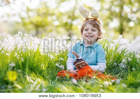Cute Happy Little Boy Wearing Easter Bunny Ears And Eating Choco