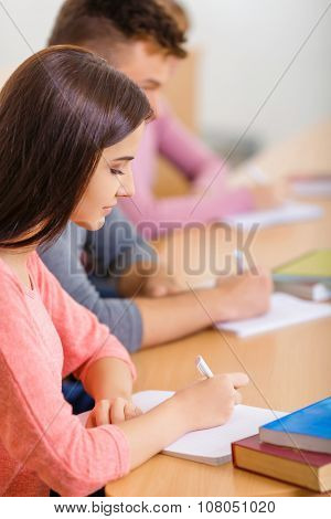 Young girl is busy making notes.