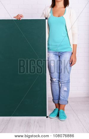 Woman in causal with green blackboard against brick wall, close up