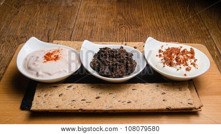 Three different sauces served on a wooden table