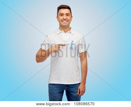 medicine, health care, gesture and people concept - smiling middle aged latin man in t-shirt with blue prostate cancer awareness ribbon pointing finger on himself