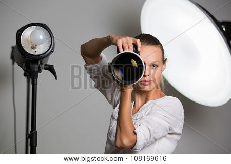 Pretty, female photographer with digital camera - DSLR and a huge telephoto lens (color toned image; shallow DOF)