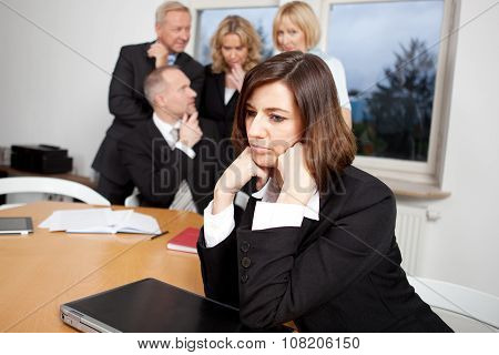 Sad businsesswoman with team in the background