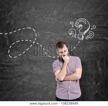 A Young Man In Casual Shirt Is Thinking About Unanswered Questions. Question Marks Are Drawn On The