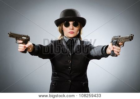 Female spy with weapon against gray