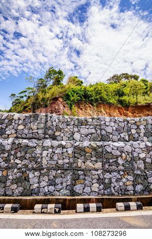 Gabion wall made of stones in the steel mesh used as a fence on a slope.