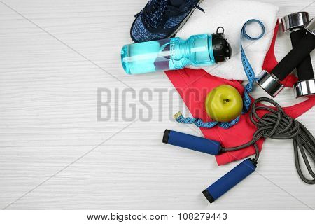 Sport clothes, shoes and sport equipment on light background