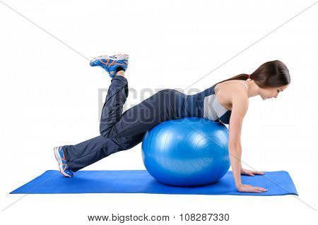 Young woman shows starting position of Fitness Stability Ball Glute Kickback Workout, isolated on white