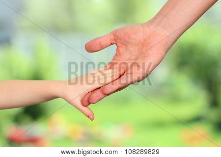 A Father  Holds The Hand Of A Small Child On A Green Background