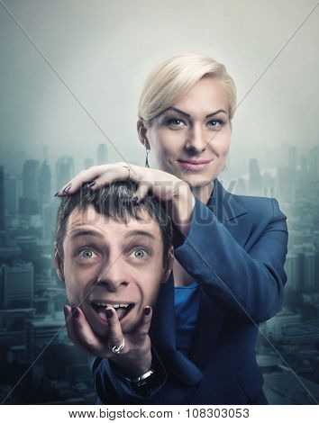 Happy businesswoman with man's head in her hand