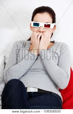 Sceared woman in 3d glasses is watching movie.