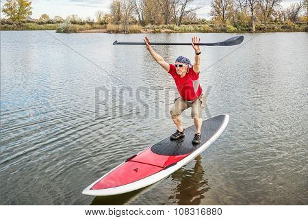 senior male paddler stretching and warming up on a paddleboard before paddling workout on a lake in Colorado