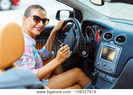 Young Pretty Woman In Sunglasses Sitting In A Convertible Car With The Keys In Hand