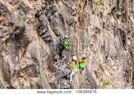 Group Of Courageous Climbers Climbing A Rock Wall