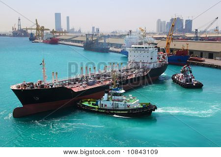 Two Boats Docked To Industrial Ship In Port Sail To Sea At Sunny Day In Abu Dhabi